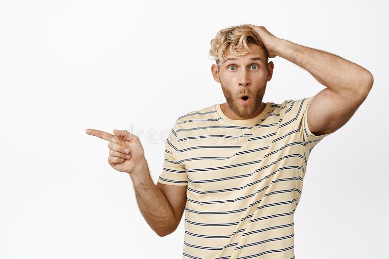 Porträt eines blonden Typen, der überrascht aussieht und links auf Promo-Verkauf weißen Hintergrund lizenzfreie stockfotografie