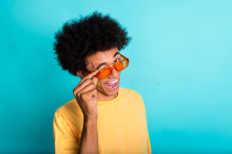 Portrait of cool confident man with afro hairstyle wear oversize t-shirt hold glasses eye winking isolated on teal color background. Portrait of cool confident man with afro hairstyle wear oversize t-shirt hold glasses eye winking isolated on teal color background.