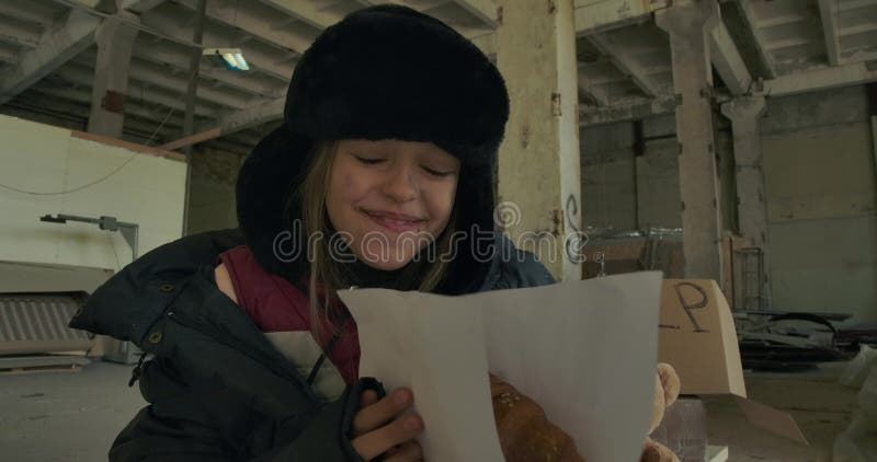 Porträt eines erschöpften kaukasischen Obdachlosen, das große Croissants und Lächelnde empfängt Hungriges, müdes Kind, das zu ess