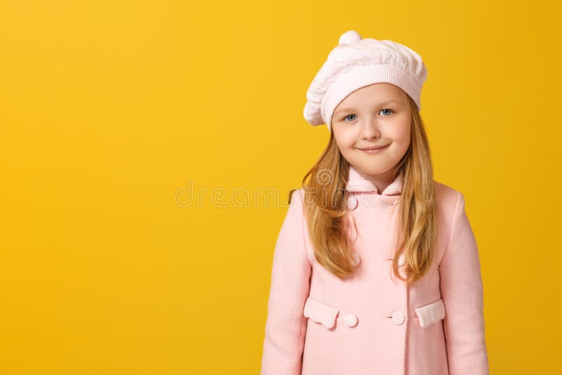 Porträt eines fröhlichen Kindes in einem rosa Mantel und einer Sitzbank auf gelbem Hintergrund Kleine Blondine schaut in die Kame stockbilder Porträt eines fröhlichen Kindes in einem rosa Mantel und einer Sitzbank auf gelbem Hintergrund Kleine Blondine schaut in die Kame stockbilder