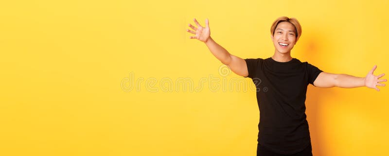 Porträt eines gut aussehenden asiatischen Mannes, der sich die Hände verteilt, um jemanden freundlichen gelben Hintergrund zu umar lizenzfreies stockbild