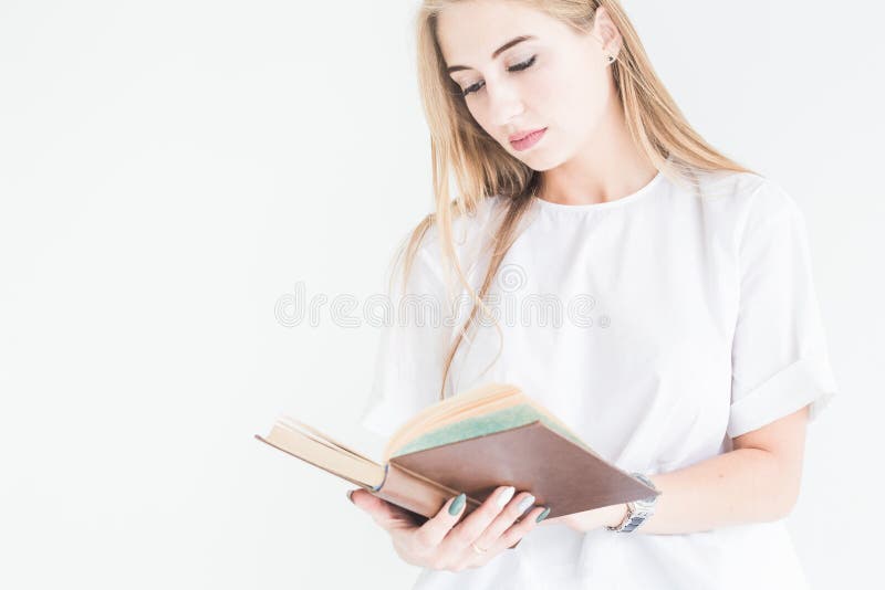 Porträt eines jungen stilvollen blonden Mädchens in einem weißen T-Shirt und in den Blue Jeans ein Buch auf einem weißen Hintergr lizenzfreies stockbild Porträt eines jungen stilvollen blonden Mädchens in einem weißen T-Shirt und in den Blue Jeans ein Buch auf einem weißen Hintergr lizenzfreies stockbild