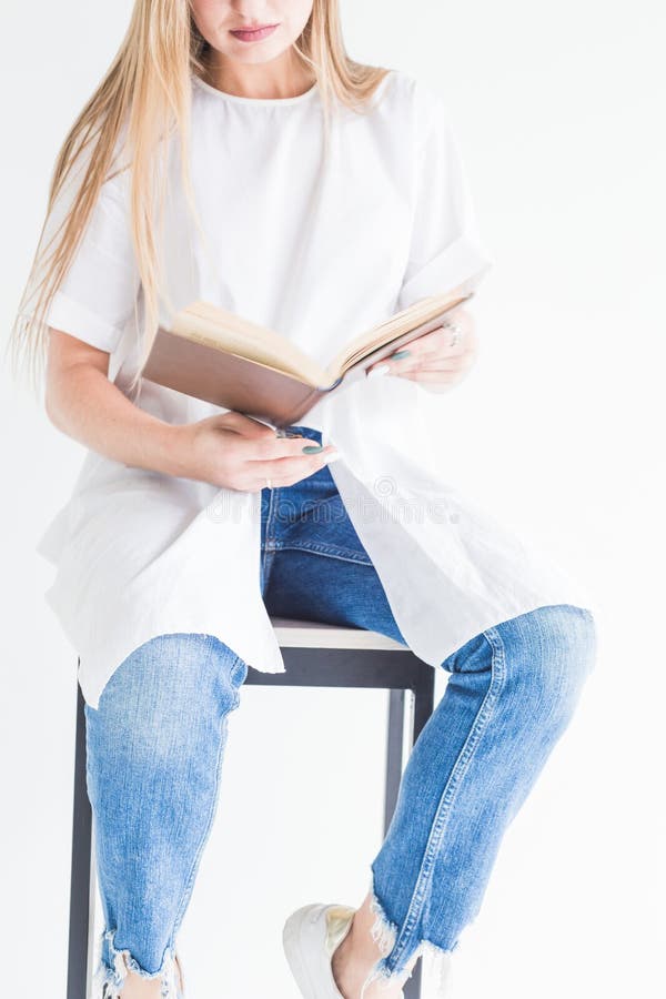 Porträt eines jungen stilvollen blonden Mädchens in einem weißen T-Shirt und in den Blue Jeans ein Buch auf einem weißen Hintergr lizenzfreie stockbilder Porträt eines jungen stilvollen blonden Mädchens in einem weißen T-Shirt und in den Blue Jeans ein Buch auf einem weißen Hintergr lizenzfreie stockbilder