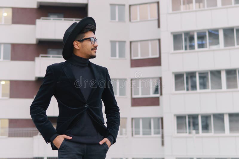 Porträt eines kühlen jungen Mannes im schwarzen Anzug und im Hut gehend auf Th stockfotografie Porträt eines kühlen jungen Mannes im schwarzen Anzug und im Hut gehend auf Th stockfotografie