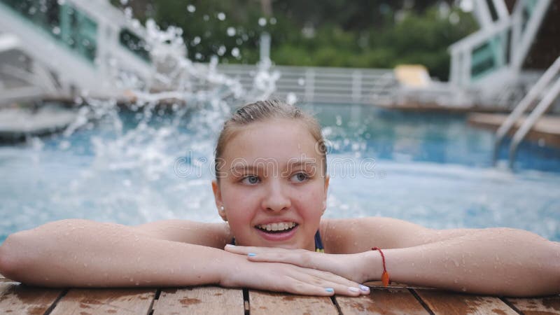 Porträt eines lächelnden Teenagermädchens mit Zahnplatten am Rande des Pools, in der Nähe