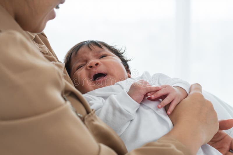 Porträt eines mehrrassigen Neugeborenen, das weint oder gähnt oder in Arm einer asiatischen Mutter liegt. Kleine süße Ausprägung d stockbild