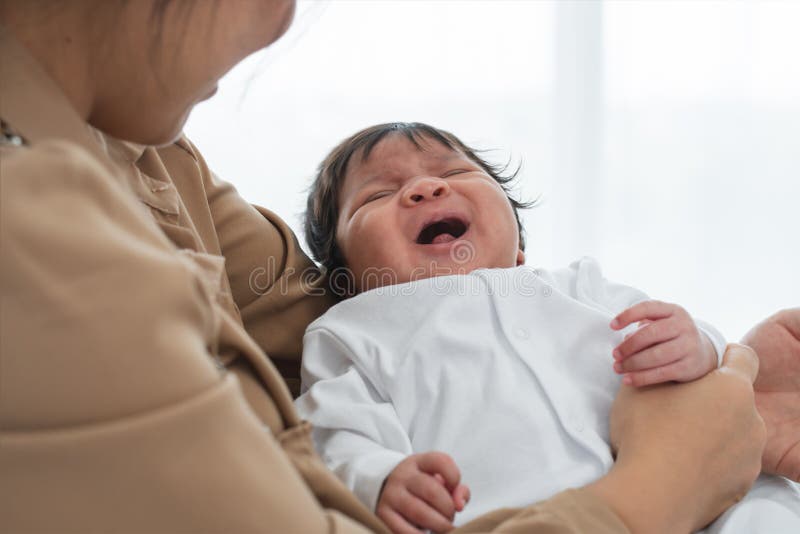 Porträt eines mehrrassigen Säuglings, das weint oder schreit und in Arm der asiatischen Mutter liegt. Kleine süße Ausprägung des S lizenzfreie stockfotos