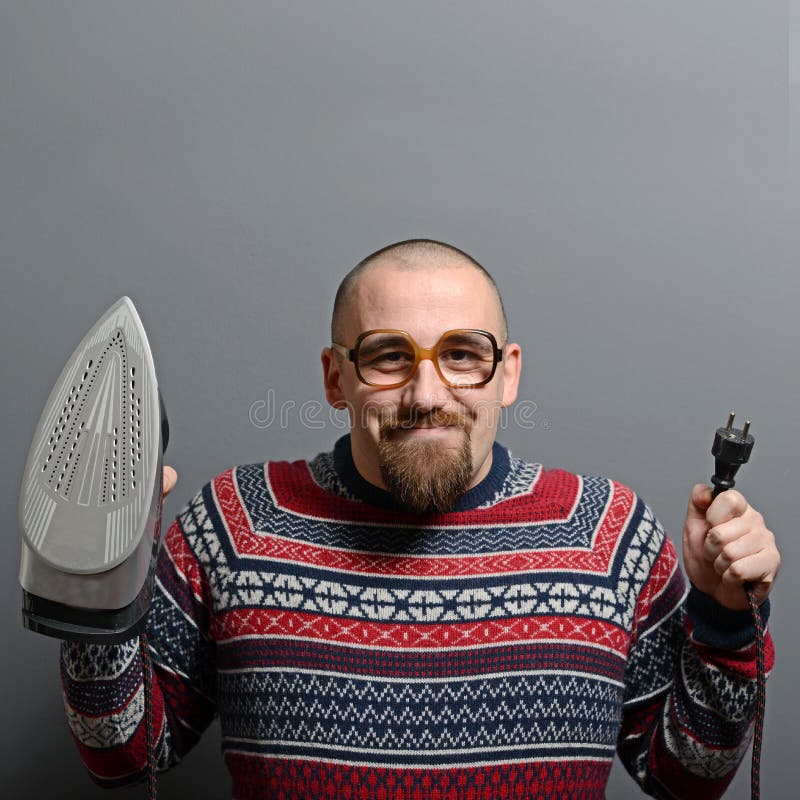 Porträt eines nerdy Mannes, der Eisen gegen grauen Hintergrund hält lizenzfreies stockbild Porträt eines nerdy Mannes, der Eisen gegen grauen Hintergrund hält lizenzfreies stockbild