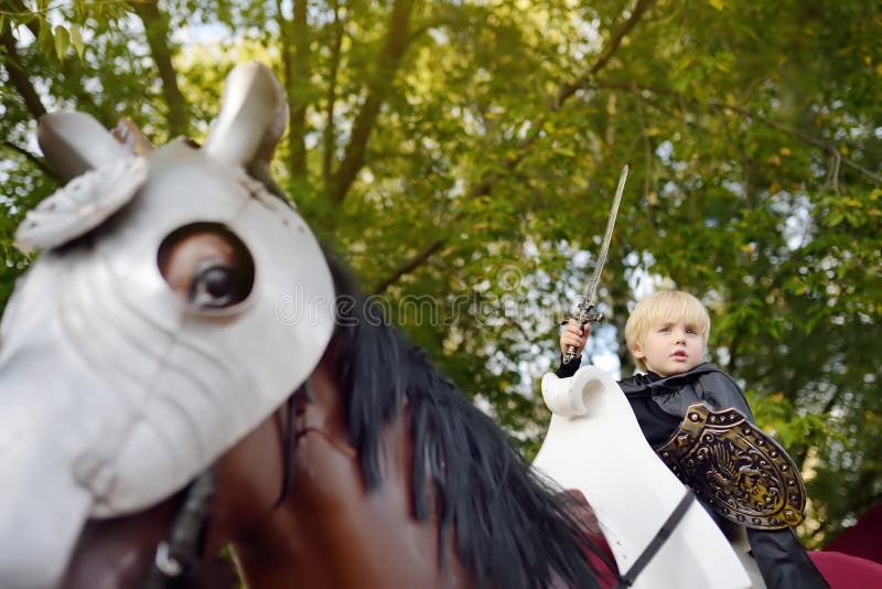 Porträt eines netten kleinen Jungen gekleidet als mittelalterlicher Ritter mit einer Klinge und einem Schild, die ein Pferd reite stockbild Porträt eines netten kleinen Jungen gekleidet als mittelalterlicher Ritter mit einer Klinge und einem Schild, die ein Pferd reite stockbild