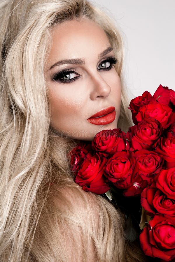 Portrait of a beautiful blonde female, girl, model with long, beautiful hair. Model in lingerie, holding red roses. Portrait of a beautiful blonde female, girl, model with long, beautiful hair. Model in lingerie, holding red roses