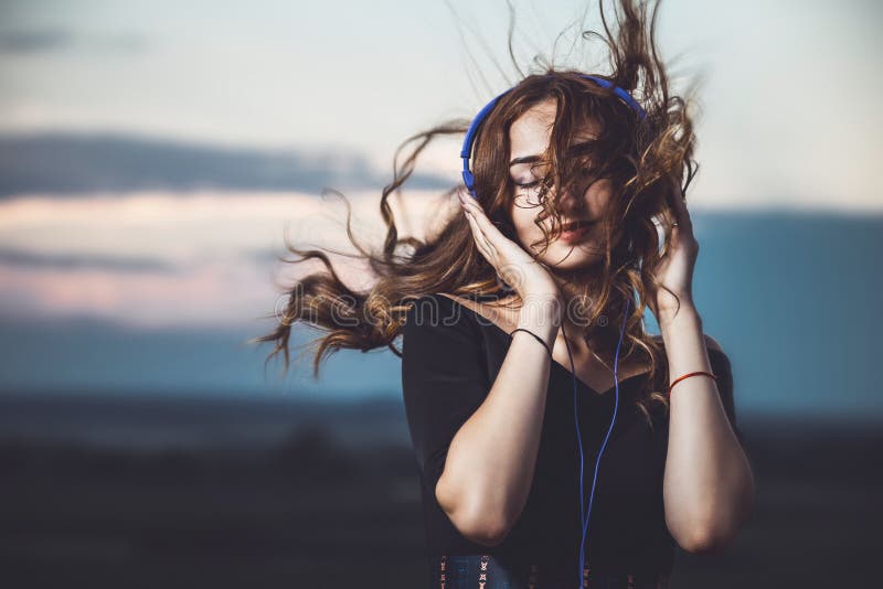 Porträt eines schönen Mädchens in den Kopfhörern hörend Musik auf Natur