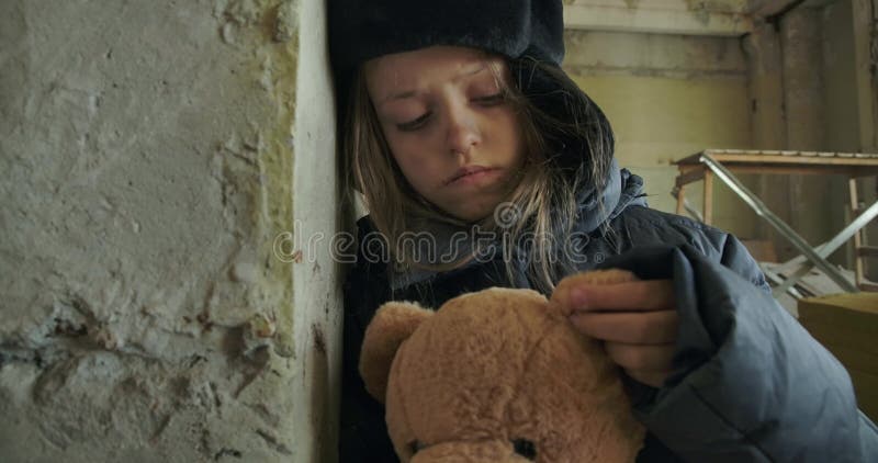 Porträt eines syrischen Flüchtlings in Winterbekleidung auf der Baustelle Kinder, die den Teddybären in Haft halten, und