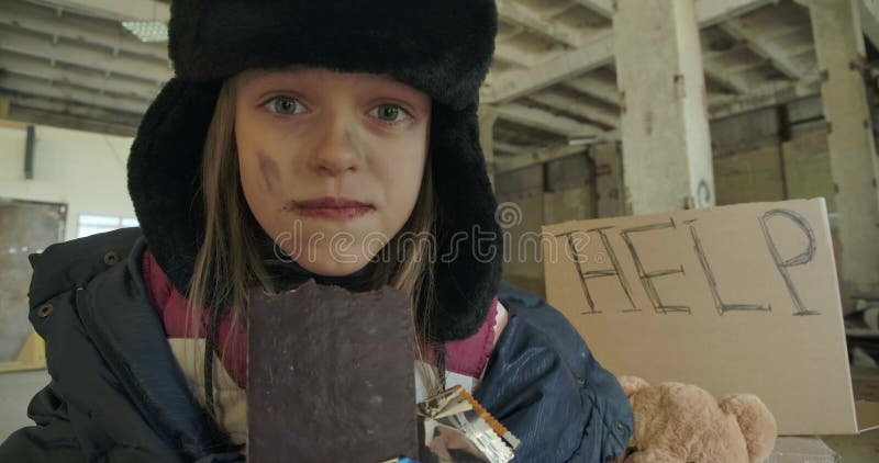 Porträt eines syrischen Mädchens mit schmutzigem Gesicht und grauen Augen, das grauenhaft die Schokoladenriegel frisst Kleiner Fl