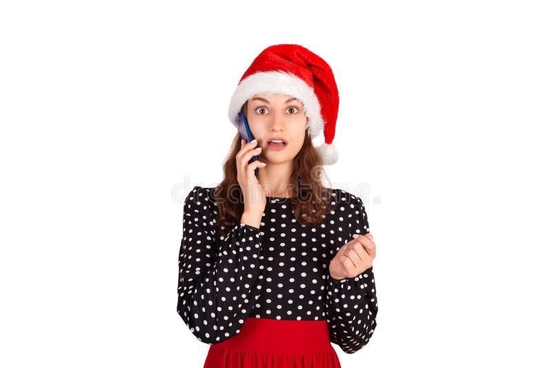 Porträt eines verwirrten netten Mädchens im Kleidergespräch am Handy emotionales Mädchen im Weihnachtsmann-Weihnachtshut lokalisi lizenzfreies stockbild Porträt eines verwirrten netten Mädchens im Kleidergespräch am Handy emotionales Mädchen im Weihnachtsmann-Weihnachtshut lokalisi lizenzfreies stockbild