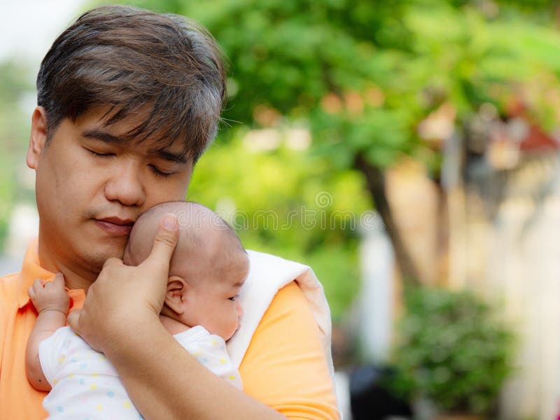 Portrait of happy Asia father holding his newborn sweet baby dressed in white clothes. The father embracing his baby with love and care. his daughter always happy when he is held. Portrait of happy Asia father holding his newborn sweet baby dressed in white clothes. The father embracing his baby with love and care. his daughter always happy when he is held.