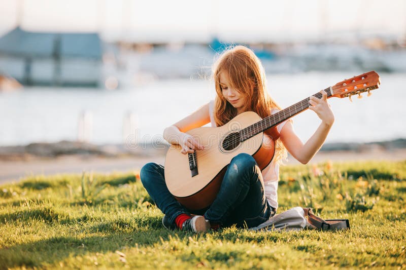 Porträt im Freien des entzückenden Mädchens mit 9-Jährigen Kinder, dasdraußen Gitarre spielt