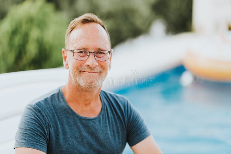 Porträt im Freien des jährigen Mannes 50, der durch das Pool stillsteht