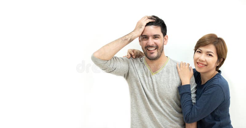 Porträt von den glücklichen jungen Paaren, die über weißer Wand stehen Lächeln und Kamera betrachtend lizenzfreie stockfotografie