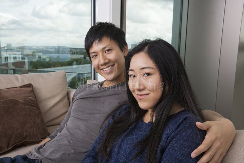 Porträt von den glücklichen liebevollen Paaren, die zu Hause auf Sofa sitzen stockfotos Porträt von den glücklichen liebevollen Paaren, die zu Hause auf Sofa sitzen stockfotos