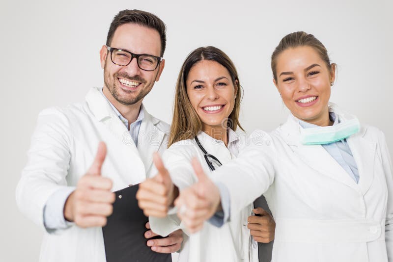 Porträt von drei glücklichen Doktoren, die lächelnd stehen und Daumen zeigen stockbild Porträt von drei glücklichen Doktoren, die lächelnd stehen und Daumen zeigen stockbild