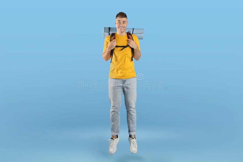 Porträt von glücklichen jungen Hipster mit Rucksack springen über blaues Studio Hintergrund stockfoto