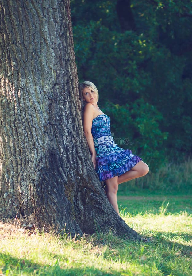 Portrait of fashionable young sensual blonde woman in garden lean on the tree. Portrait of fashionable young sensual blonde woman in garden lean on the tree.