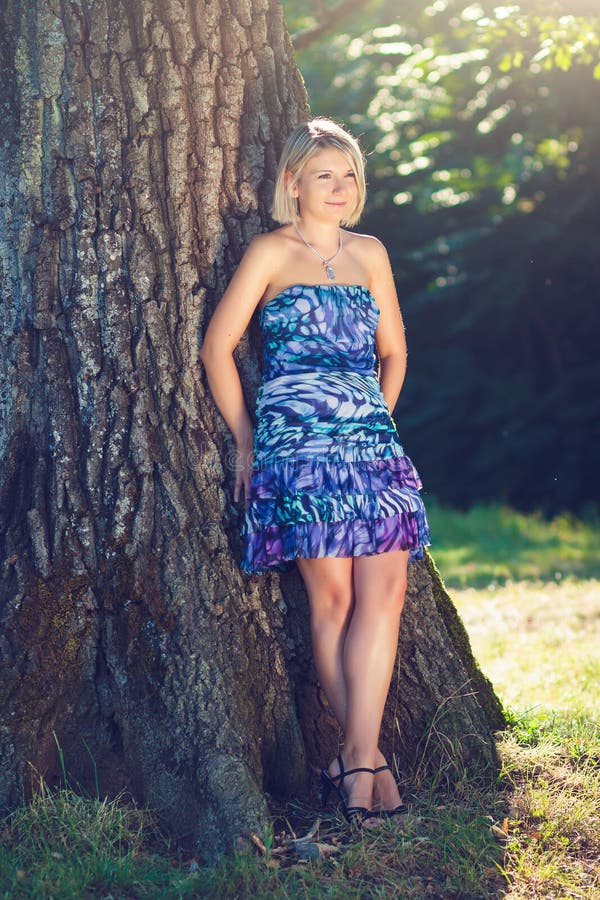 Portrait of fashionable young sensual blonde woman in garden lean on the tree. Portrait of fashionable young sensual blonde woman in garden lean on the tree.