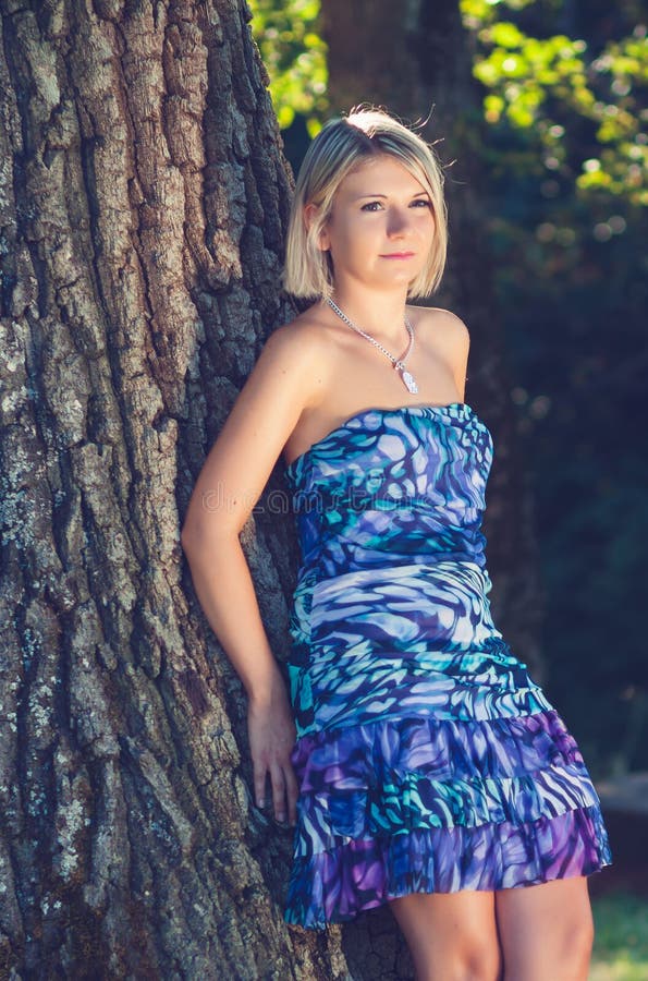 Portrait of fashionable young sensual blonde woman in garden lean on the tree. Portrait of fashionable young sensual blonde woman in garden lean on the tree.