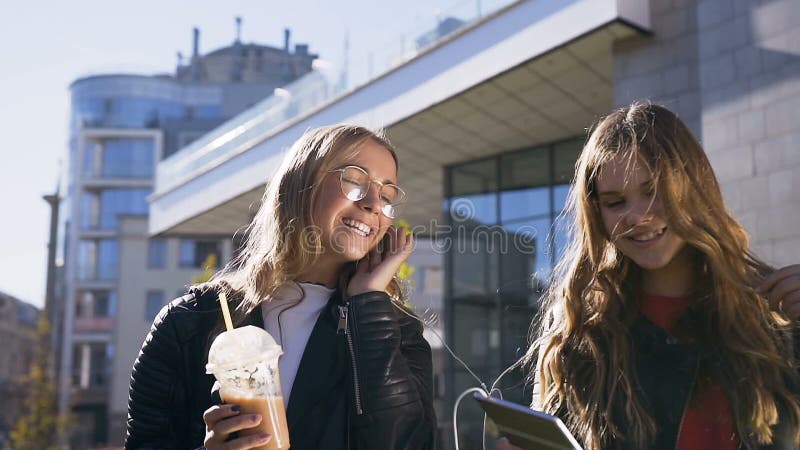 Porträt von zwei jungen kaukasischen Frauen, die digitale Tablette verwenden und glücklich beim Gehen im Stadtzentrum lächeln stock video footage Porträt von zwei jungen kaukasischen Frauen, die digitale Tablette verwenden und glücklich beim Gehen im Stadtzentrum lächeln stock video footage