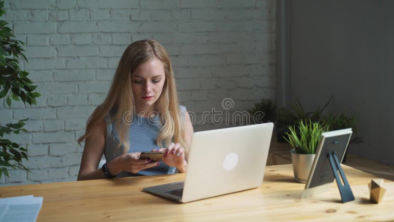 Porträtaufnahme einer kreativen Frau, die an ihrem Schreibtisch sitzt Unter Verwendung des Notizbuches Sie sitzt in einem Licht u