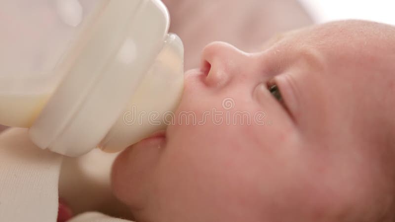 Porträtkleinkind, das verdünntes Milchpulver trinkt. trinkende Muttermilch des Kaukasus Neugeborenen vom kleinen Plastikbaby