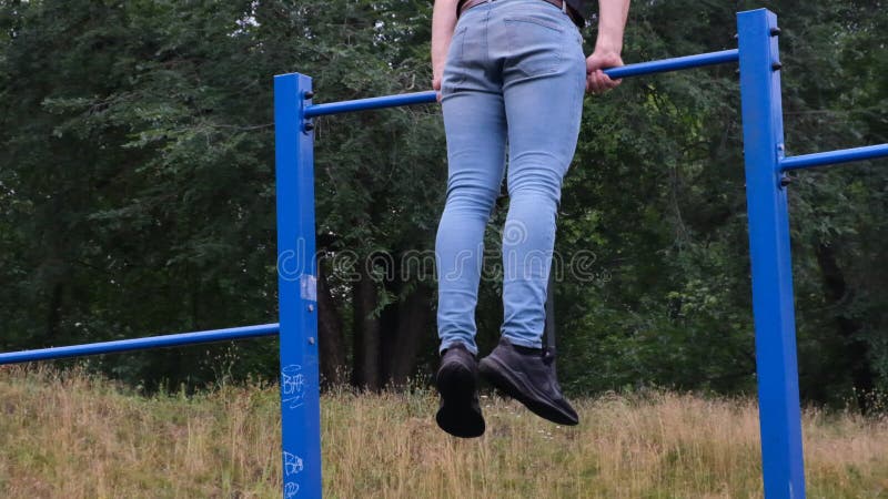 Porträtt av en ung man som gör trupper på den horisontella baren utomhus på en gatulekplats en stark idrottsman arkivfilmer