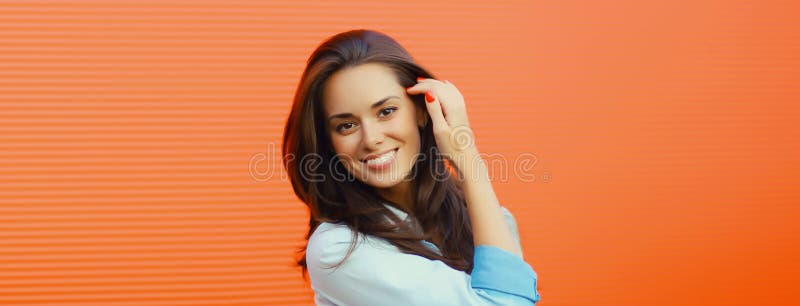 Porträtt av en vacker, glad, leende brunette, ung kvinna som pockar på orange royaltyfria bilder