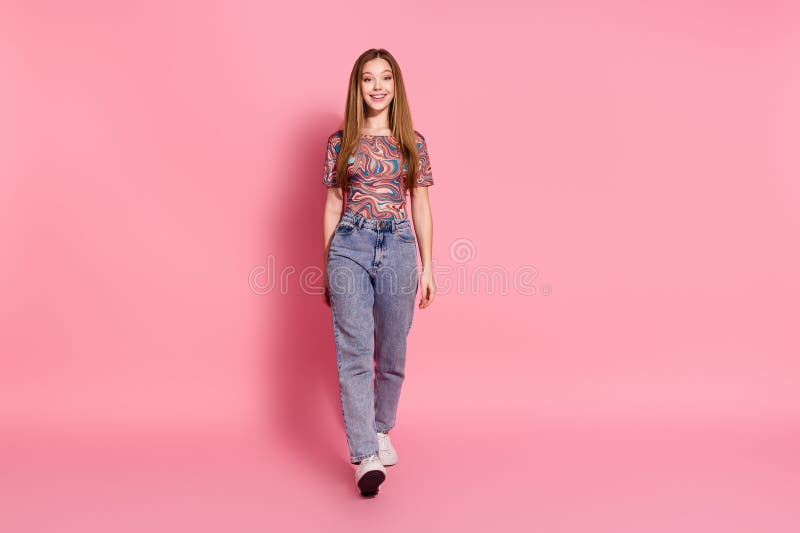 Portrait of cheerful friendly good mood teen girl wear colorful t-shirt stylish jeans pants walking isolated on pink color background. Portrait of cheerful friendly good mood teen girl wear colorful t-shirt stylish jeans pants walking isolated on pink color background.