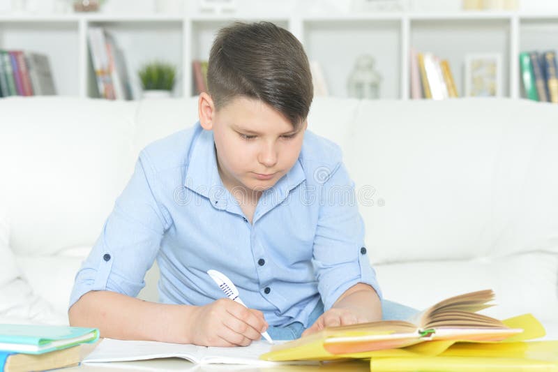 Porträtt av pojken som gör hemläxor hemma arkivfoto