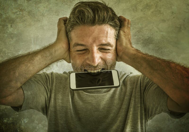 Dramatic portrait of sick and crazy stressed man biting mobile phone screaming desperate and hysteric looking like a weirdo in life problem and stress concept  on grunge background. Dramatic portrait of sick and crazy stressed man biting mobile phone screaming desperate and hysteric looking like a weirdo in life problem and stress concept  on grunge background