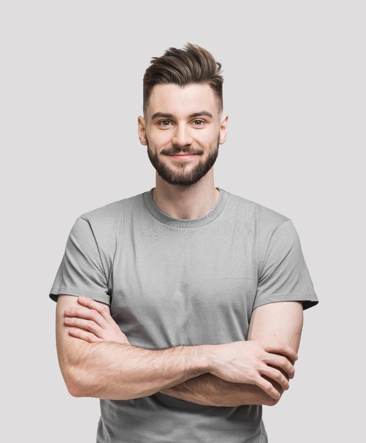 Portrait of handsome smiling young man with folded arms. Smiling joyful cheerful men with crossed hands studio shot. Isolated on gray background. Portrait of handsome smiling young man with folded arms. Smiling joyful cheerful men with crossed hands studio shot. Isolated on gray background