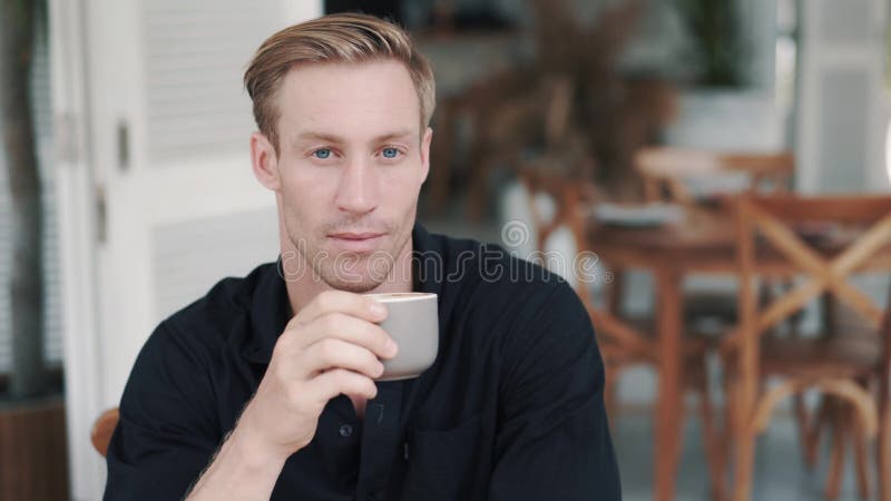 Porträtt av stilig man som dricker kaffe i kaféet tittar på kameran och ler stock video