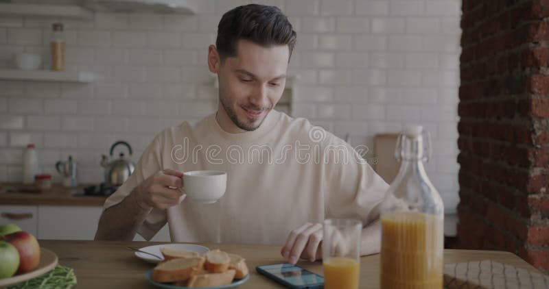 Porträtt av studentkaffe till frukost och användning av smartphone i lätt kök hemma