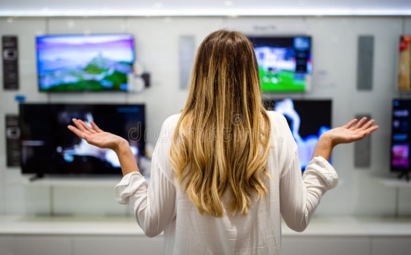 Porträtt av unga kvinnor som har svårt att välja i förråd av digitala apparater. royaltyfria foton