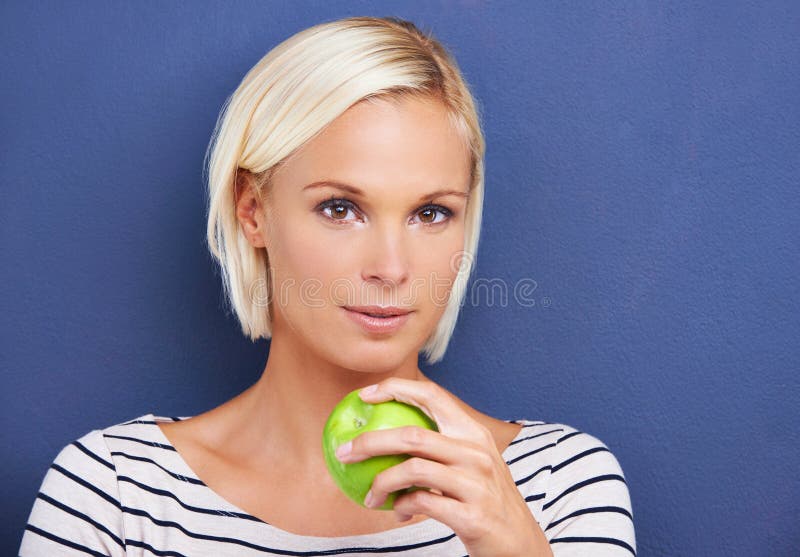 Porträtt och äpple i studio för näringsintag på blå bakgrund eller fruktvitaminmellanmål eller fruktfiber. kvinnlig royaltyfri fotografi