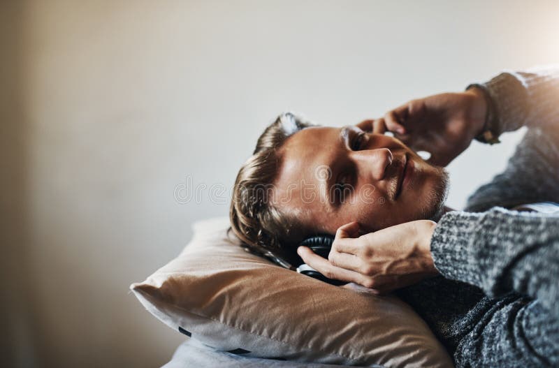 Porträtthörlurar och glad man i sängen för strömmande slappna av och poddsändning på morgonen. Teknikleende och musik arkivfoton