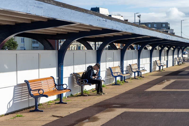 A young man sitting alone on a bench with his head in his hands stock photos A young man sitting alone on a bench with his head in his hands stock photos