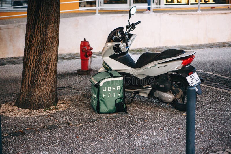Portugal, Lisbon 29 april 2018: Food delivery Uber eats. Motorcycle and on the ground the basket of food that says Uber stock photos Portugal, Lisbon 29 april 2018: Food delivery Uber eats. Motorcycle and on the ground the basket of food that says Uber stock photos