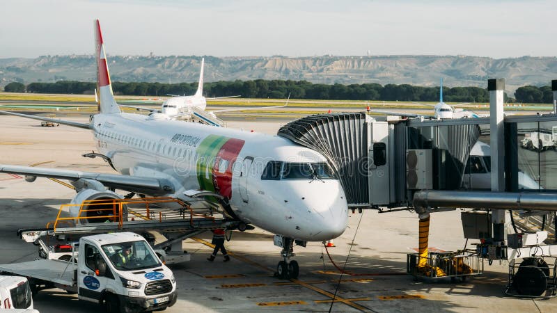 Madrid Bajaras, Spain - Dec 23, 2019: Portuguese airliner Tap with boarding bridge while maintainance crew doing checks. Madrid Bajaras, Spain - Dec 23, 2019: Portuguese airliner Tap with boarding bridge while maintainance crew doing checks