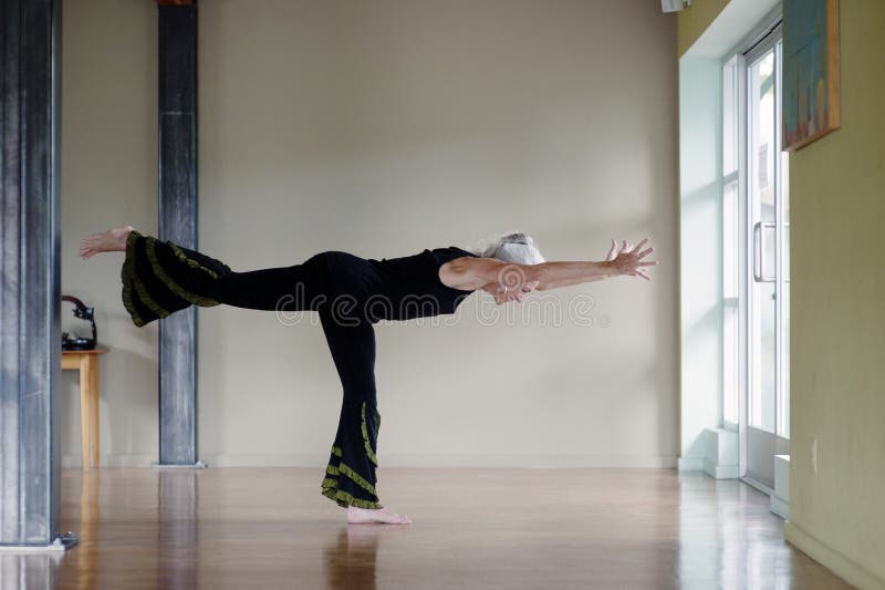 Posa matura di yoga del guerriero III della donna immagini stock libere da diritti Posa matura di yoga del guerriero III della donna immagini stock libere da diritti