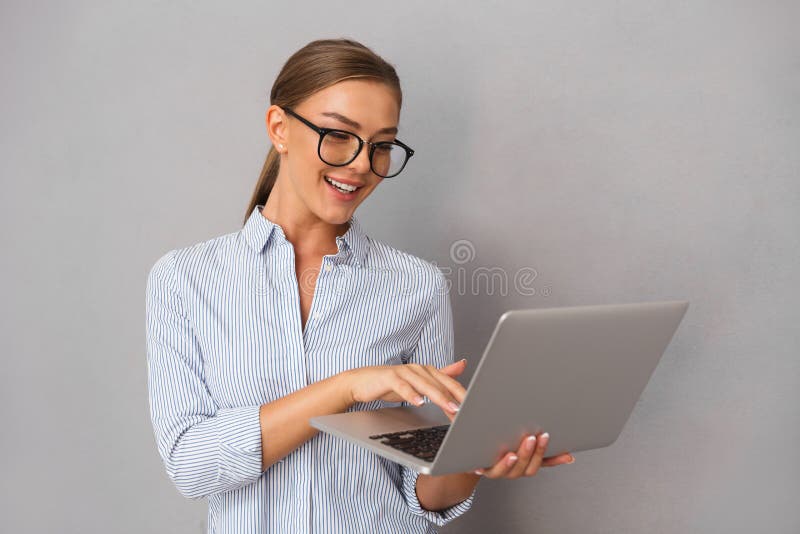Pose de jeune femme d'affaires d'isolement au-dessus du fond gris de mur utilisant l'ordinateur portable