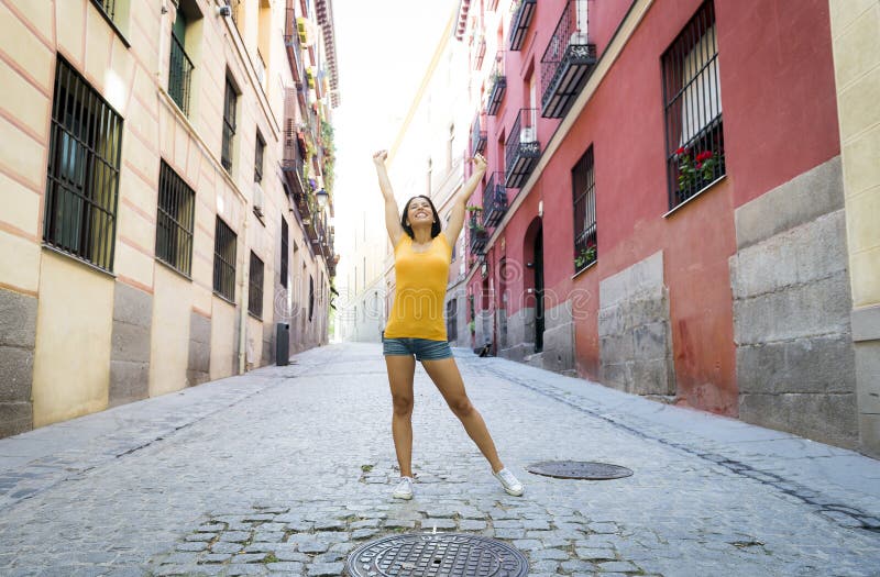 Pose heureuse et enthousiaste de jeune femme latine attirante sur la ville européenne urbaine moderne photos libres de droits Pose heureuse et enthousiaste de jeune femme latine attirante sur la ville européenne urbaine moderne photos libres de droits
