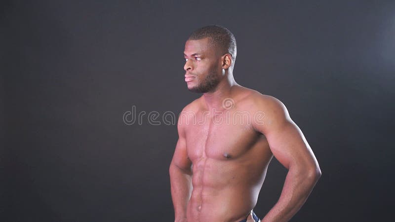 Pose masculine africaine attrayante de combattant ou de boxeur sans chemise, d'isolement au-dessus du fond foncé