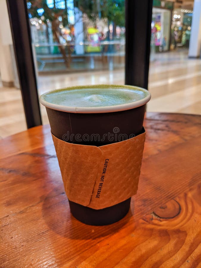 Poser du latte de thé vert matcha chaud avec le couvercle éteint photographie stock libre de droits Poser du latte de thé vert matcha chaud avec le couvercle éteint photographie stock libre de droits